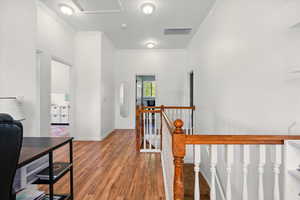 Hall with an upstairs landing, crown molding, wood finished floors, and baseboards