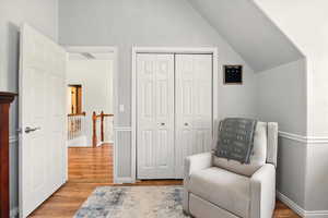Sitting room featuring wood finished floors, lofted ceiling, an upstairs landing, and baseboards