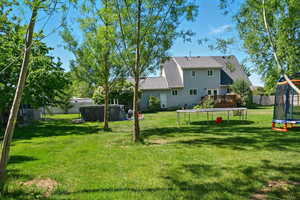 View of yard featuring a trampoline and a deck