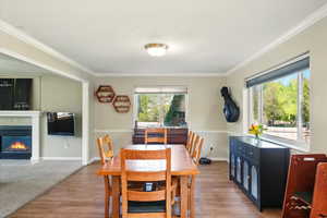Dining space featuring ornamental molding, wood finished floors, a glass covered fireplace, and baseboards