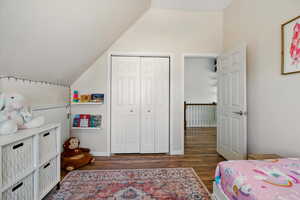 Bedroom with vaulted ceiling, wood finished floors, and a closet