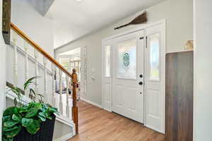 Entryway with light wood-style flooring, stairway, and baseboards