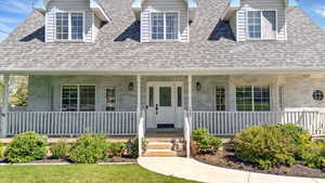 New england style home with covered porch and a shingled roof