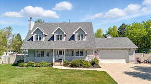 New england style home featuring an attached garage, a chimney, concrete driveway, and a shingled roof