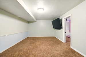 Carpeted spare room featuring a textured ceiling and baseboards