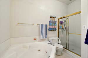 Full bath featuring toilet, a shower stall, and a whirlpool tub