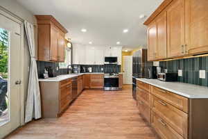 Kitchen with appliances with stainless steel finishes, tasteful backsplash, light wood finished floors, recessed lighting, and light countertops