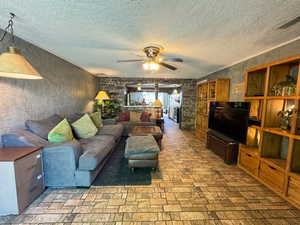 Living area with a ceiling fan and a textured ceiling
