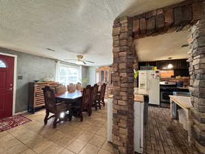 Dining area with a textured ceiling, ceiling fan, and ornate columns
