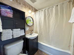Full bathroom with vanity, shower / bath combo with shower curtain, toilet, and tile patterned floors