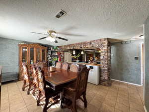 Dining room with light tile patterned flooring, ceiling fan, and a textured ceiling