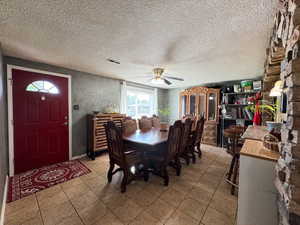 Dining room with a ceiling fan, light tile patterned flooring, and a textured ceiling
