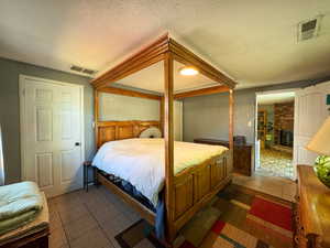 Bedroom featuring tile patterned floors, a fireplace, and a textured ceiling