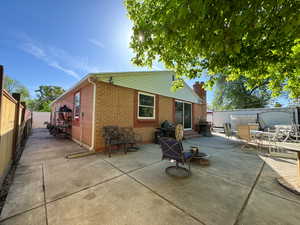 Back of house with brick siding, entry steps, a patio area, a fenced backyard, and outdoor dining space