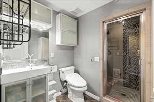 Bathroom with a stall shower, toilet, vanity, and baseboards