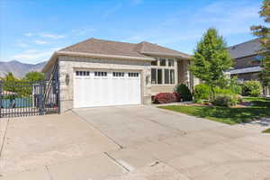 View of front of home featuring a garage, concrete driveway, a mountain view, and stone siding