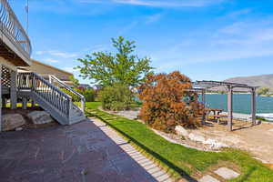 View of patio featuring a pergola, stairway, and a deck with water view