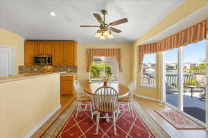 Dining room with light wood-type flooring, baseboards, a ceiling fan, and a textured ceiling