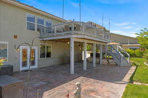 Back of property featuring a patio, a wooden deck, and stucco siding