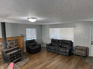 Living room with wood finished floors, a textured ceiling, and a wood stove