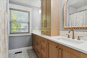 Full primary bathroom with double vanity, quartz countertops, custom cabinet champagne brass faucets and metal finishes, with colonial baseboards