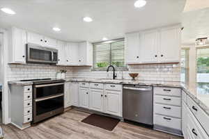 Kitchen with healthy amount of natural light, white cabinetry, and recessed lighting