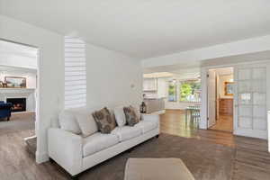 Living room with wood laminate flooring, a lit fireplace, and tall colonial baseboards