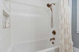 Full primary bathroom with champagne brass shower / bathtub combination, full wall tile and a larger/taller tub.