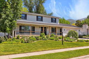 View of front of home featuring a garage, a mountain view, a front yard, covered porch, and brick siding