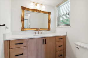 Half bath with vanity, quartz countertop, champagne brass faucet, and toilet