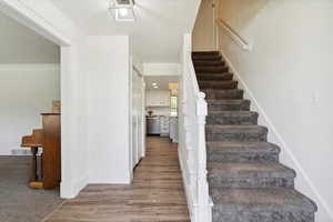 Staircase with wood laminate flooring and tall colonial baseboards