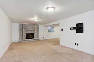 Finished basement den area featuring carpet flooring, a textured ceiling, a fireplace, and baseboards