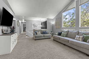 Carpeted living area with a brick fireplace, textured ceiling, and large windows