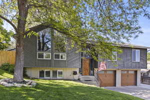 Split entry with 2 car garage, wood siding and landscaping