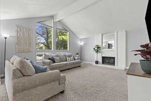 Carpeted living area with a brick fireplace, textured ceiling, and large windows