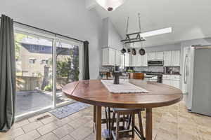 Dining space featuring high vaulted ceiling and light stone tile flooring