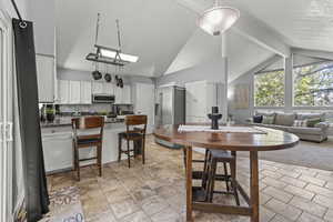 Dining space featuring high vaulted ceiling and light stone tile flooring