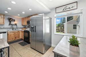 Kitchen featuring appliances with stainless steel finishes, light countertops, light tile patterned floors, recessed lighting, and light brown cabinetry