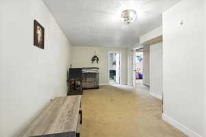 Living area featuring light carpet and a textured ceiling