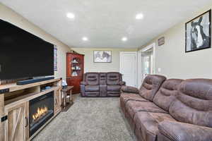 Living room featuring light colored carpet, recessed lighting, and a glass covered fireplace