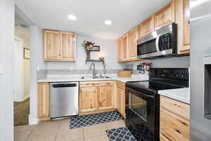 Kitchen featuring appliances with stainless steel finishes, light brown cabinetry, light countertops, light tile patterned flooring, and recessed lighting