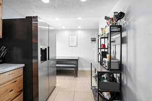 Kitchen with stainless steel fridge with ice dispenser, light tile patterned floors, recessed lighting, and a textured ceiling