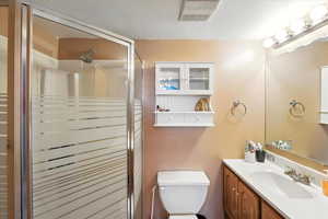 Bathroom with vanity, a stall shower, and a textured ceiling