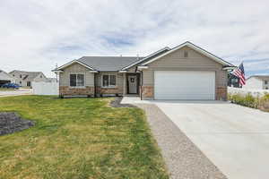 View of front of house with an attached garage, driveway, stone siding, and board and batten siding