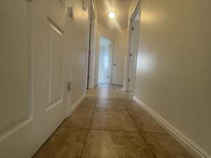 Hallway with light tile patterned floors and baseboards