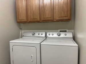 Washroom featuring independent washer and dryer and cabinet space