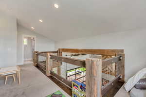 Hall with an upstairs landing, vaulted ceiling, baseboards, and recessed lighting