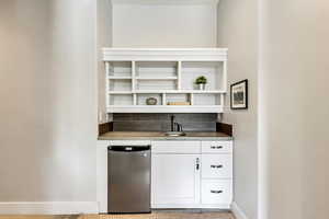 Indoor wet bar with fridge, baseboards, and tasteful backsplash
