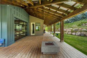Wooden terrace with an outdoor fire pit and a yard