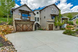Craftsman inspired home with stone siding, board and batten siding, an attached garage, and concrete driveway